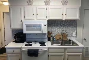 a white kitchen with a stove and a microwave at The Luxe Lakefront in Lake Ozark