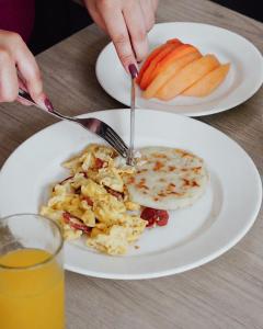 a person eating a breakfast plate of eggs and fruit at Hotel Viña Del Mar in Santa Marta