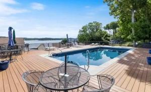 a swimming pool with tables and chairs on a wooden deck at Lake Front Lookout in Lake Ozark