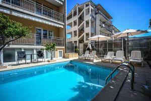 a swimming pool with chairs and umbrellas next to a building at Mikuljan Apartments with Pool-5 min to Beach & Private Parking Included in Stobreč