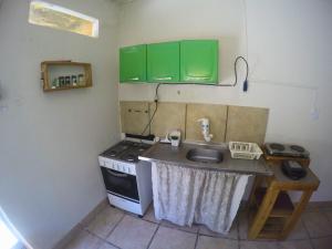 a kitchen with a sink and a stove and green cabinets at Canto da Onda - Trilha exclusiva para a praia in Marechal Deodoro