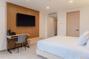 a bedroom with a bed and a desk and a television at Hotel Luure Bosque Real in Mexico City