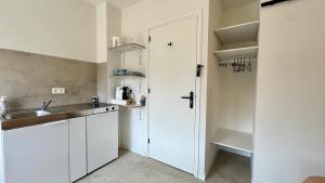 a white kitchen with a sink and a refrigerator at Stationbeds Studio-2 Alkmaar in Alkmaar