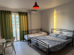 two beds in a room with a table and chairs at Apartments Kristi in Shëngjin