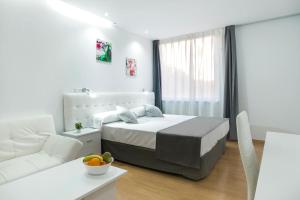 een witte slaapkamer met een bed en een witte bank bij Boutique Urban Madrid Génova in Madrid