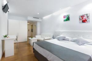 a white bedroom with a bed and a living room at Boutique Urban Madrid Génova in Madrid