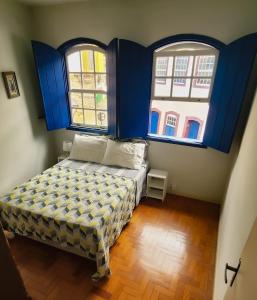 a bedroom with blue walls and two windows and a bed at Casa Carmo in Ouro Preto