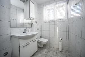 a white bathroom with a sink and a toilet at Mikuljan Apartments- Free Parking -5 Min by Walk to Beach in Stobreč +55 photos