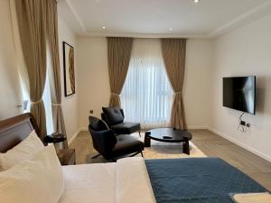 a hotel room with a bed and a chair and a television at ASFARO Apartments in Abuja