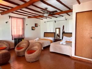 a bedroom with two beds and wicker chairs at Choby's House Holbox in Holbox Island
