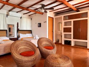 a bedroom with two beds and two wicker chairs at Choby's House Holbox in Holbox Island