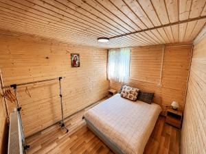 ein kleines Schlafzimmer mit einem Bett in einem Holzzimmer in der Unterkunft Cabana IBU in Bumbueşti