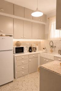 a kitchen with white cabinets and a white refrigerator at VERADO by A&D Properties in Porto Rafti