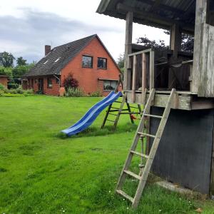 a playground with a slide in a yard with a house at Kulumheide in Löwenstedt