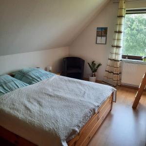 a bedroom with a bed and a chair and a window at Kulumheide in Löwenstedt