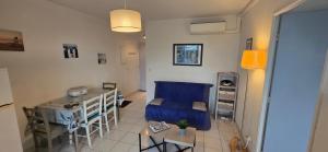 a living room with a blue chair and a table at Calme et indépendant avec clim, wifi et parking - 2e étage sans ascenseur in Canet-en-Roussillon