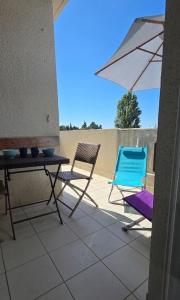 two chairs and a table and an umbrella on a patio at Calme et indépendant avec clim, wifi et parking - 2e étage sans ascenseur in Canet-en-Roussillon