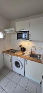 a kitchen with a washing machine and a microwave at Calme et indépendant avec clim, wifi et parking - 2e étage sans ascenseur in Canet-en-Roussillon
