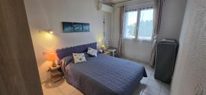 a small bedroom with a blue bed and a window at Calme et indépendant avec clim, wifi et parking - 2e étage sans ascenseur in Canet-en-Roussillon