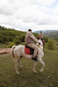 two people riding on a white horse in a field at Villa Lugina e Kuajve Bulqize in Bulqizë