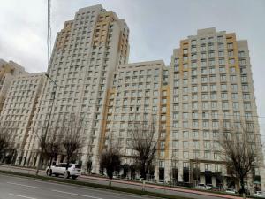 a large building with a white van parked in front of it at Современные 2-комнатные апартаменты в ЖК Capital City рядом с Shym City Park in Shymkent