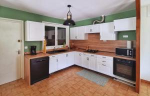 a kitchen with white cabinets and a black dishwasher at Calme entre pins et océan in Onesse-et-Laharie