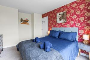 a bedroom with a blue bed with red wallpaper at Great Sutton House Perfect for Contractors in Sutton