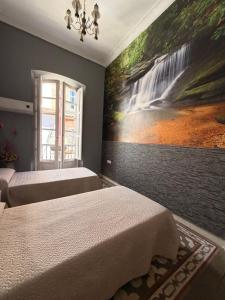 a bedroom with two beds and a painting on the wall at Great House Almería in Almería