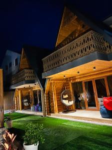 a large wooden building with a green lawn in front of it at Cottages Vakhrama in Abastumani