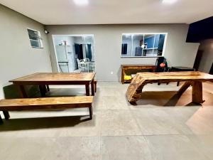 two wooden tables and benches in a room at chácara 3A-2 in Pôrto Feliz