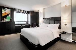 a bedroom with a large white bed and a chair at Hôtel Alt Québec in Quebec City