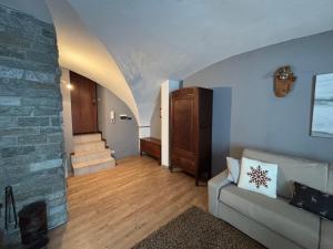 a living room with a couch and a stone wall at Appartamento Grangia Rigat, Bousson, Cesana Torinese in Bousson +3 photos