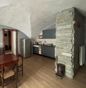 a kitchen with a stone wall and a table and a dining room at Appartamento Grangia Rigat, Bousson, Cesana Torinese in Bousson