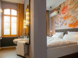 a bedroom with a bed and a sink and a mirror at WELTRAD Parkhotel am Fluss in Schönebeck +11 photos