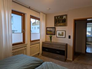 a bedroom with a bed and a dresser and windows at Kunst am Marktplatz in Niederwerrn