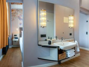a bathroom with a sink and a mirror at WELTRAD Parkhotel am Fluss in Schönebeck