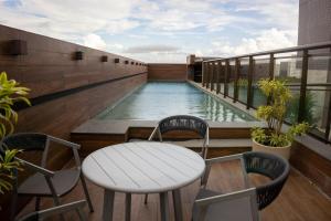 a swimming pool on a balcony with a table and chairs at Studio premium aconchegante vista mar in São Luís