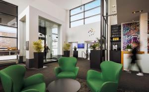 a lobby with green chairs and people walking in the background at Hôtel Alt Québec in Quebec City