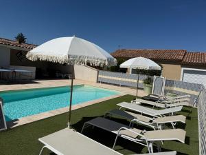 a group of lawn chairs with an umbrella next to a swimming pool at Gites de la Casasole in Vogüé