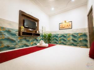 a room with a television and a red carpet at K D Dham Hotel- Near Prem Mandir & Iskcon Temple Vrindavan in Vrindāvan