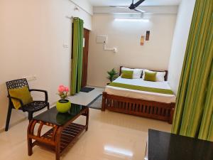 a bedroom with a bed and a chair and a table at Krishna Theeram 150m from Temple in Guruvāyūr +3 photos
