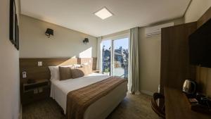a hotel room with a bed and a large window at Augusta Centro Hotel in Canela