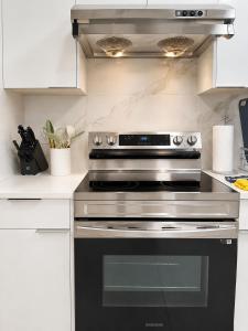 a black oven in a kitchen with white cabinets at Modern Vancouver 2BR Suite Full Kitchen & Laundry in Vancouver