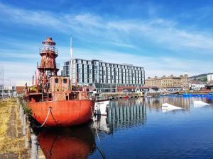 a red boat in the water next to a lighthouse at Right Choice by 3 Crowns in Dundee