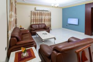 a living room with leather furniture and a flat screen tv at Fursan Apartment in Manama