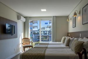 a hotel room with two beds and a window at Augusta Centro Hotel in Canela