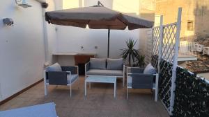 a patio with two chairs and an umbrella at Archimede29 in Syracuse