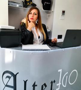 eine Frau sitzt mit einem Laptop an einem Schreibtisch in der Unterkunft Alterego B&B in Milazzo