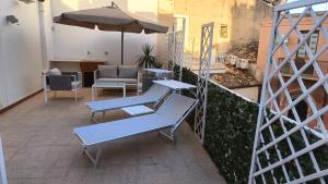 a patio with benches and an umbrella on a balcony at Archimede29 in Syracuse