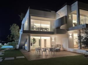 a house with a table and chairs on a deck at night at Like at Home - Boutique A6 Sea view, Private Terrace & Pool in Palau